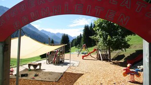 A playground with a red archway labeled "Kinderspaßplatze Brunnenleiten" and various play equipment.