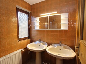 A bathroom with two sinks, a window with blinds, and a mirror above the sinks. - Holiday Home Near Zell am See and Kaprun (Bruck an der Grossglocknerstrasse)