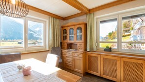 Eine Küche mit Holzausstattung, einem Esstisch und großen Fenstern mit Blick auf die Berge.