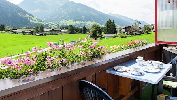Ein Balkon mit Tee-Tisch, der auf ein grünes Feld und Berge blickt.