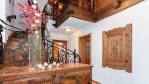 A wooden chest of drawers with metal handles and a decorative emblem, a staircase with wrought iron railings, and a wooden door with carved designs. - Great Group Holiday Home (Neukirchen am Grossvenediger)