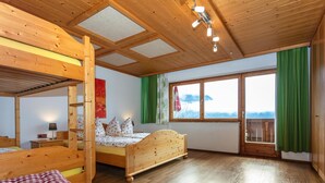 A wooden cabin with bunk beds, a large window with a view, and a wooden ceiling. - Great Group Holiday Home (Neukirchen am Grossvenediger)