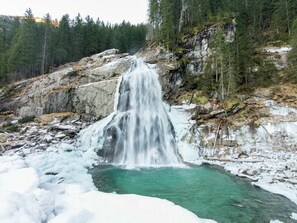 A waterfall cascading into a clear turquoise pool surrounded by rocky terrain and sparse vegetation. - Cozy Apartment in Wald- Konigsleiten (Wald im Pinzgau)