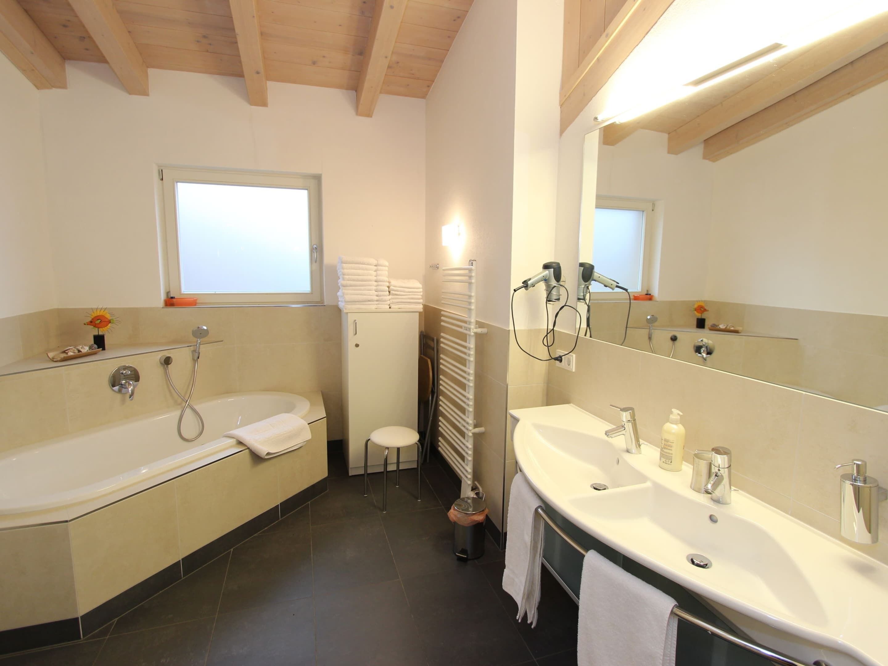 A bathroom with a bathtub, a sink, and a mirror.