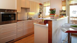 Eine moderne Küche mit Edelstahlgeräten, Holzschränken und einer Bar, dekoriert mit einer bunten Blumenvase.