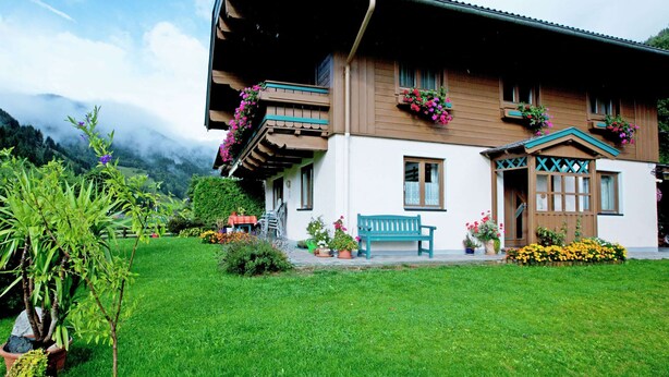 A traditional chalet with a sloped roof, wooden balconies with flower boxes, and a well-maintained lawn. - Apartment in Viehhofen Near Ski Lifts (Viehhofen)