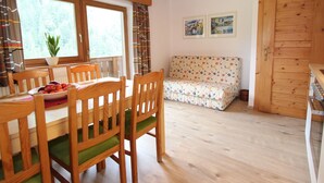 A cozy room with a wooden dining table, chairs, a sofa, and a wooden door. - Apartment in Viehhofen Near Ski Lifts (Viehhofen)