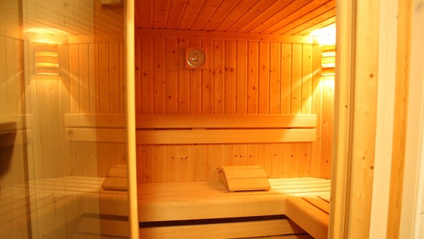 A sauna with wooden walls and benches, a visible clock, and a glass partition. - Large Holiday Home With Plenty of Privacy (Flachau)