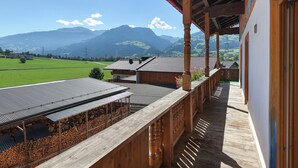 Un balcon en bois offrant une vue sur une montagne et un champ verdoyant.