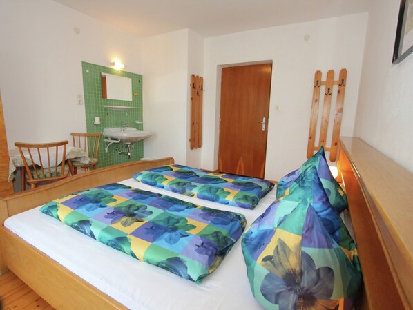 A room with two beds, a wooden chair, a small table, a sink, and a mirror. - Sunlit Farmhouse near Hochzillertal Ski Area in Tyrol (Hart im Zillertal)