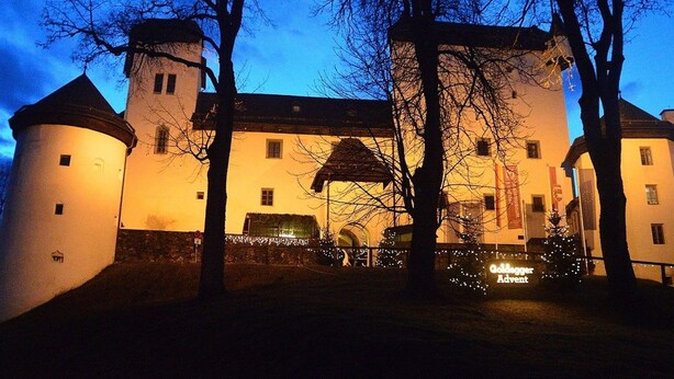 A historic building with a central tower, a round tower to the left, and a smaller tower to the right.