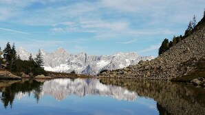 A tranquil lake with a clear reflection of the surrounding mountains and trees.