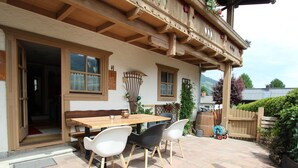 Un patio al aire libre con una mesa y sillas de madera, una valla de madera y vistas del paisaje circundante.