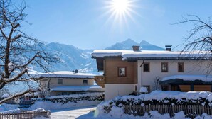 Un edificio cubierto de nieve con una valla de madera y montañas al fondo.