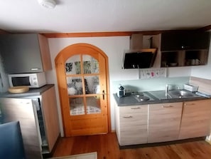 A compact kitchen with a microwave, a sink, and wooden cabinets.