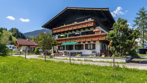 Ein zweigeschossiges Gebäude mit schrägem Dach, hölzernen Balkonen und Außenbereichen zum Sitzen.
