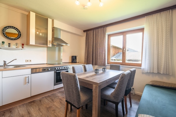 A modern kitchen with white cabinets, a stainless steel stove, and a dining table with four chairs.