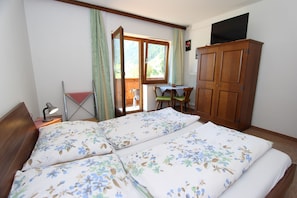 A bedroom with a bed, a desk, and a wardrobe.