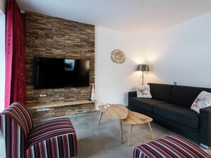 Relax in this stylish living room with a flat-screen TV, sofa, armchairs, and a coffee table.