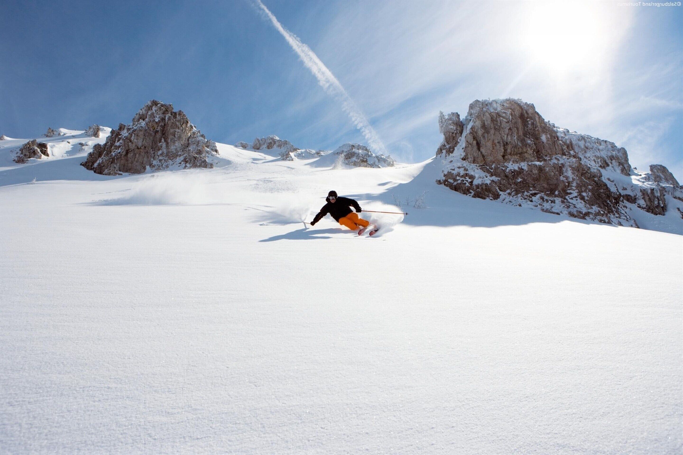 A snowy mountain landscape with a skier in motion.