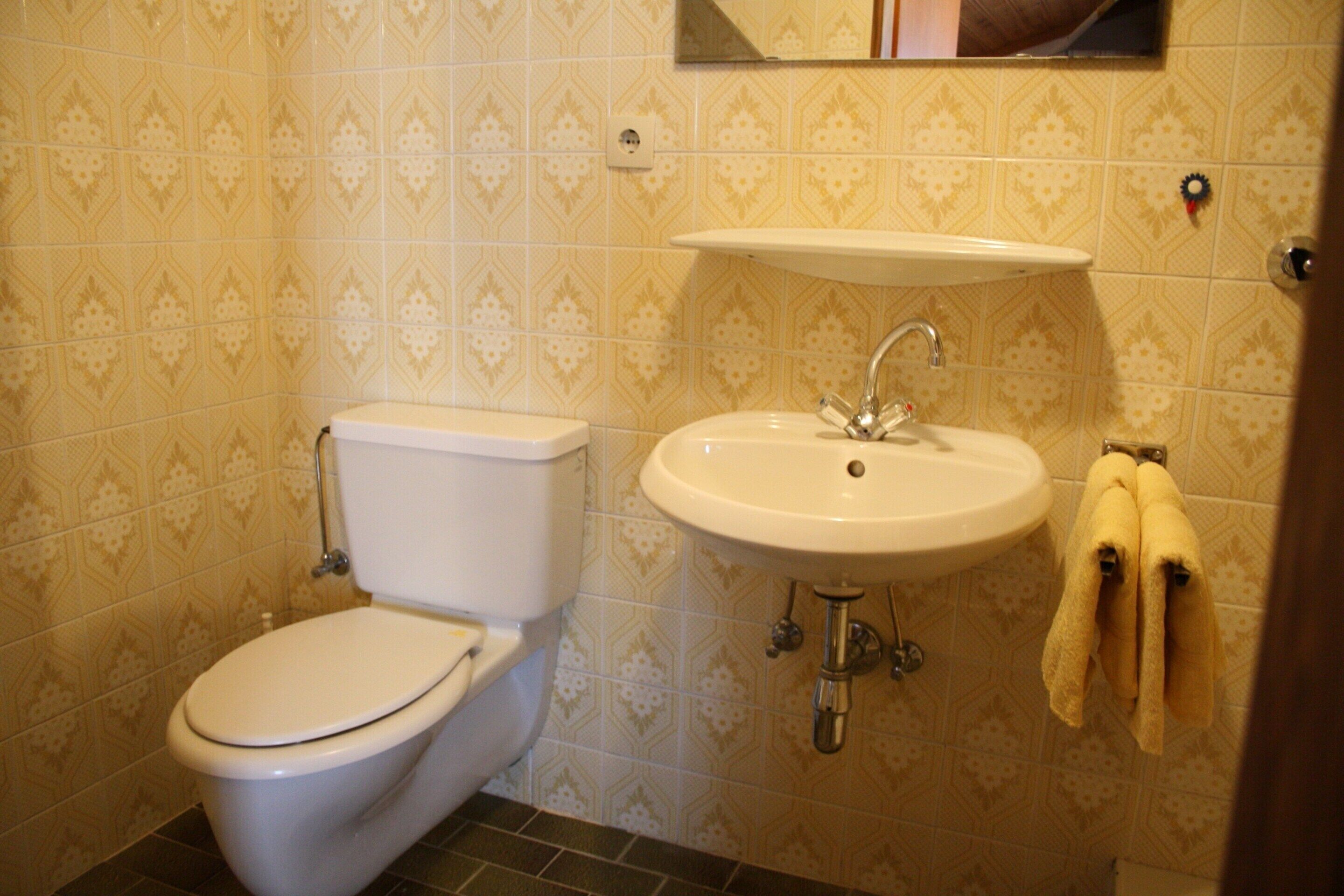 A bathroom with a toilet, sink, and towel rack.