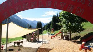 A playground with a red archway reading "UNDERSPIELPLAT BRUNNLEITEN" and various play equipment. - Simplistic Apartment in Kleinar near Cross Country Skiing (Kleinarl)
