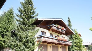 A multi-story building with balconies, surrounded by tall evergreen trees. - Simplistic Apartment in Kleinar near Cross Country Skiing (Kleinarl)