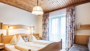 A wooden bed with a headboard, a bedside table, a nightstand, and a bench with a patterned cushion. - Simplistic Apartment in Kleinar near Cross Country Skiing (Kleinarl)