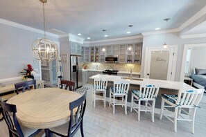 A modern kitchen with a central island, white cabinetry, and pendant lighting.