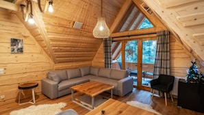 A cozy cabin interior with a wooden interior, a gray sofa, a wooden coffee table, and a small Christmas tree. - Zakopiana (Zakopane)