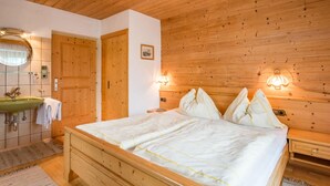 Un dormitorio con cama de madera, cabecera de madera, mesita de noche, armario de madera, un espejo, un lavamanos y una toalla.