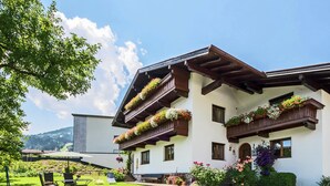 A multi-story building with balconies adorned with flowers, a well-maintained lawn, and a clear view of the surrounding landscape. - Vintage Apartment in Fügen near Ski Area (Fuegen)