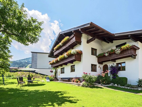 Un edificio de varios pisos con balcones decorados con flores, un césped bien cuidado y una vista despejada del paisaje circundante.