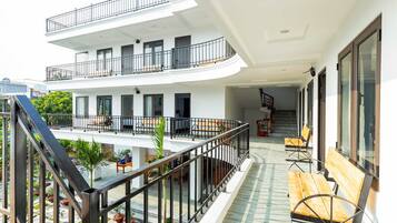 A multi-level building with balconies, outdoor seating, and a staircase.