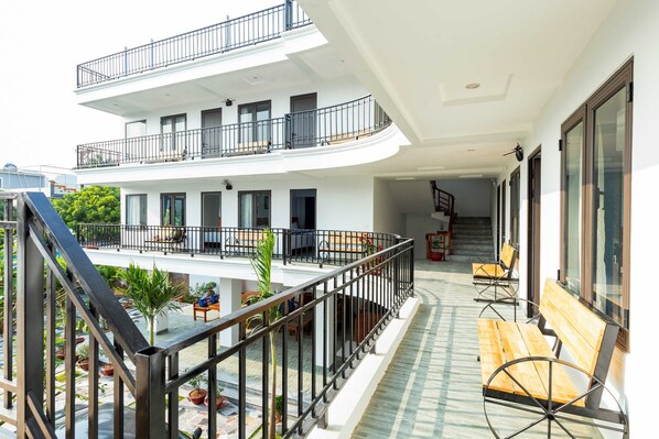 Un edificio de varios niveles con balcones, asientos al aire libre y una escalera.