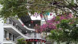 A multi-story building with balconies, a stone-paved courtyard, and parked motorcycles. - Elizabeth Hotel Tam Coc (Nam Hoa Lu)