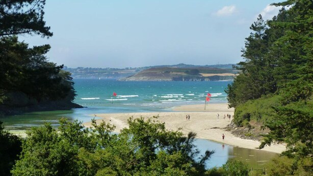 A coastal beach with clear waters, a sandy shore, and dense greenery. - Country house Quevarec (Dinéault)