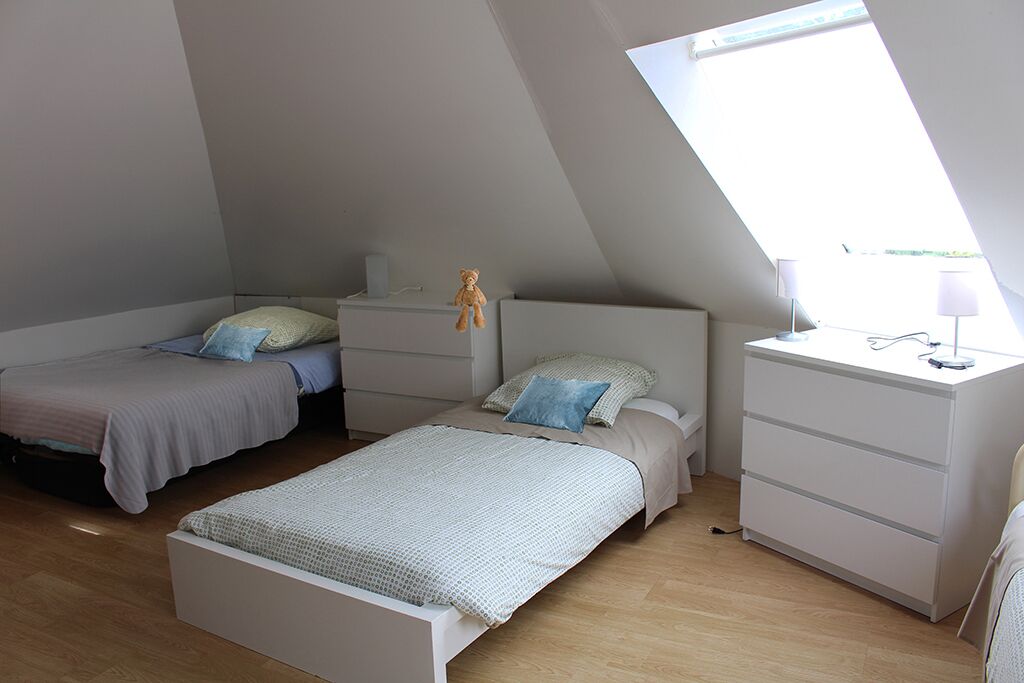 Une chambre avec deux lits, un bureau et une fenêtre.