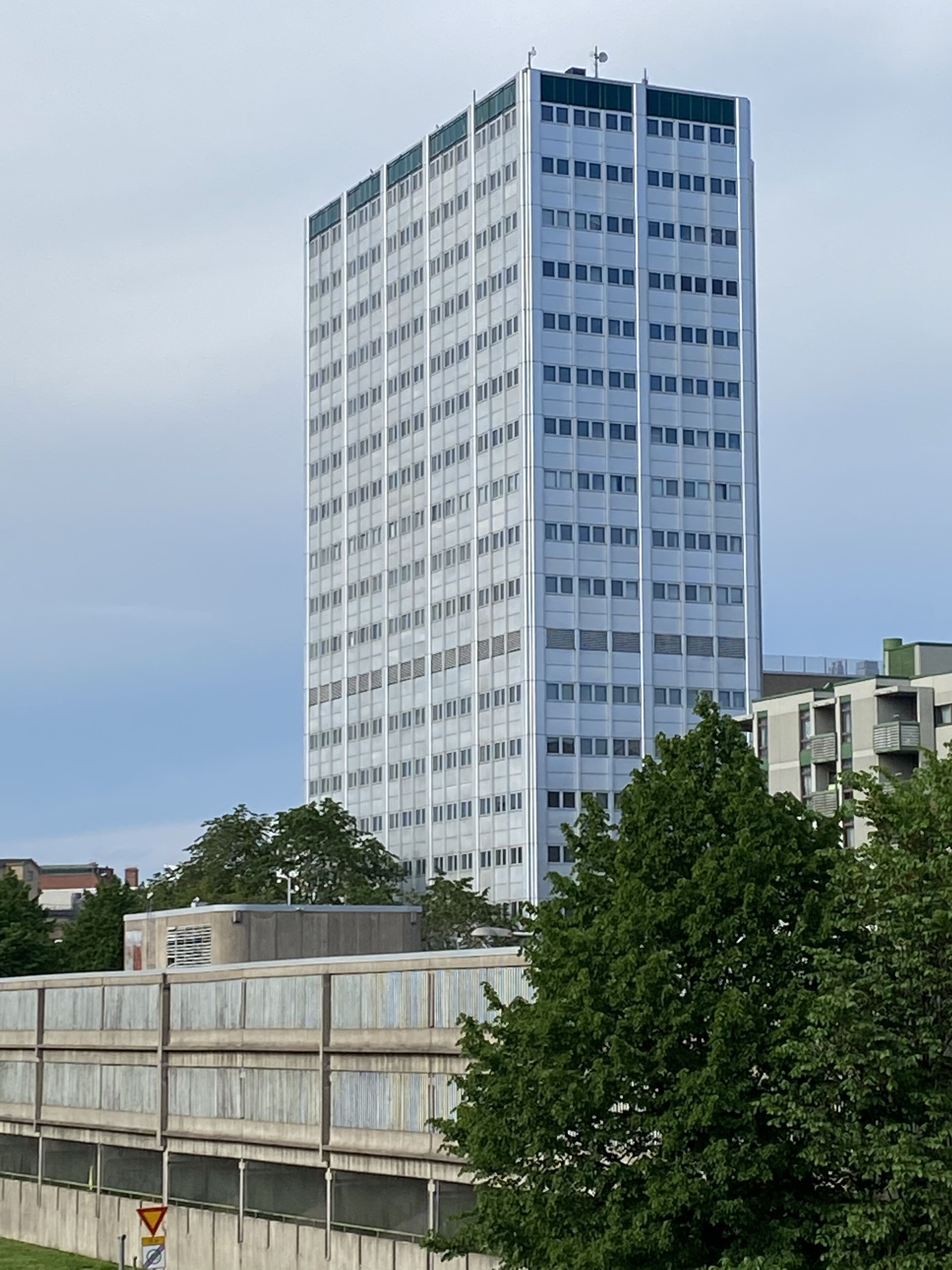 Ein hohes, modernes Gebäude mit einer gitterförmigen Fassade und vielen Fenstern.