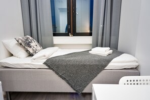 Cozy retreat with a single bed, grey bedspread, and a white chair.