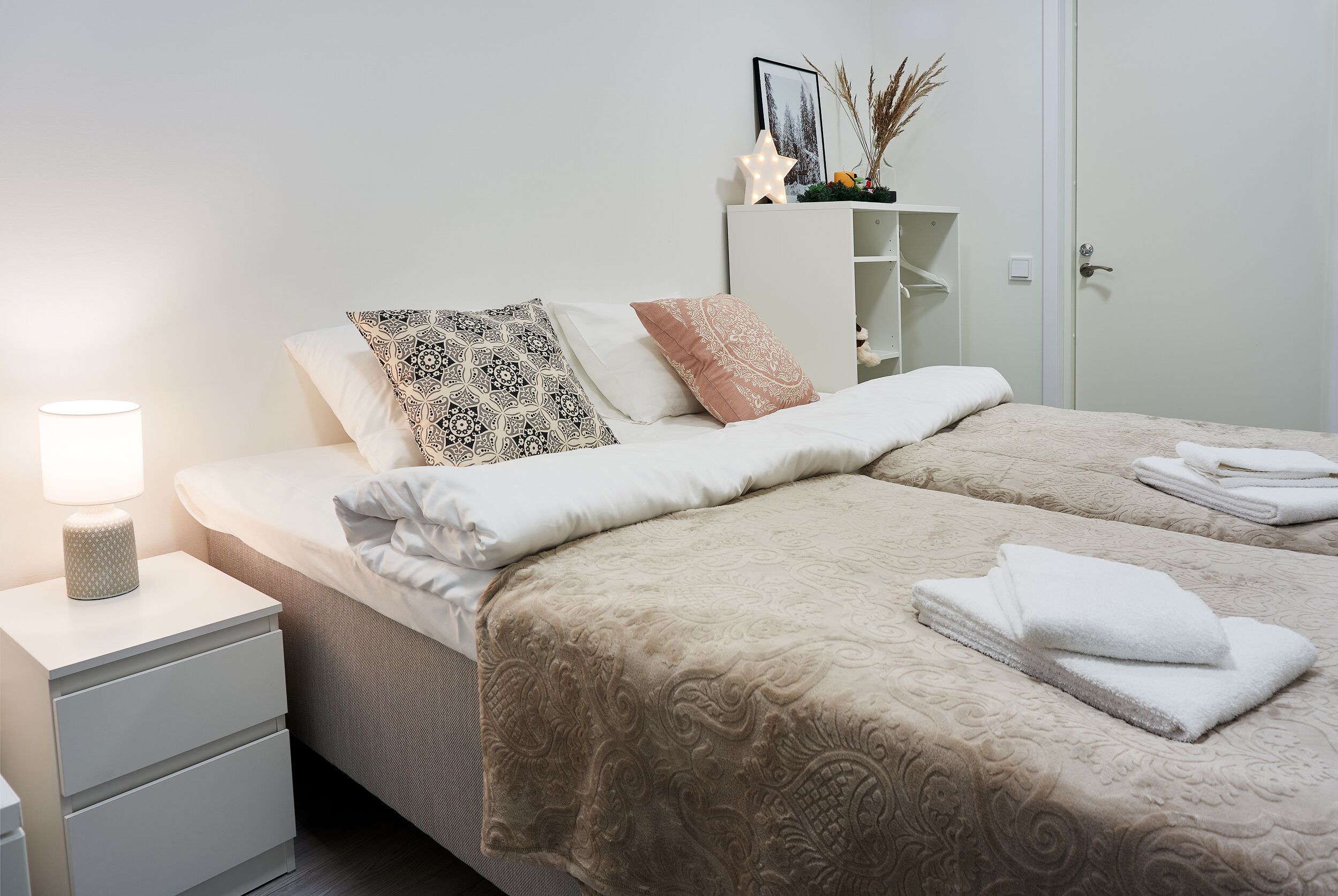 A neatly arranged bedroom with a bed, bedside table, and a wardrobe.