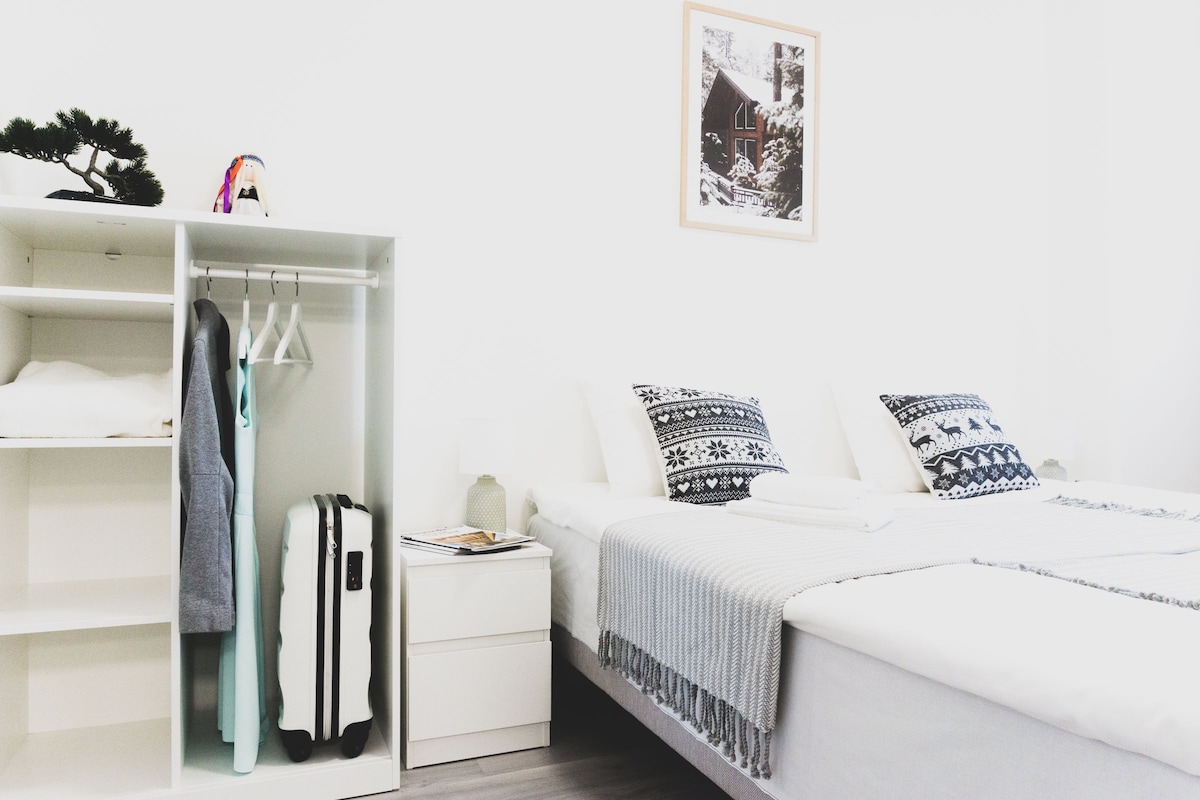 A bedroom with a bed, a wardrobe, a nightstand, and a small table.