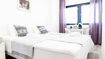 A neatly arranged bedroom with a bed, pillows, a bedside table, and a window with curtains.