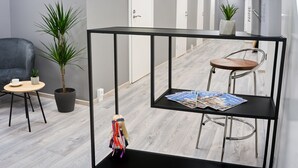 Un espace de bureau moderne avec une table en métal noir, une plante en pot, une chaise et une poupée.