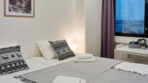 Une chambre d’hôtel avec un grand lit, deux oreillers, une couverture, une table de chevet, une lampe, une fenêtre avec des rideaux et un téléviseur.