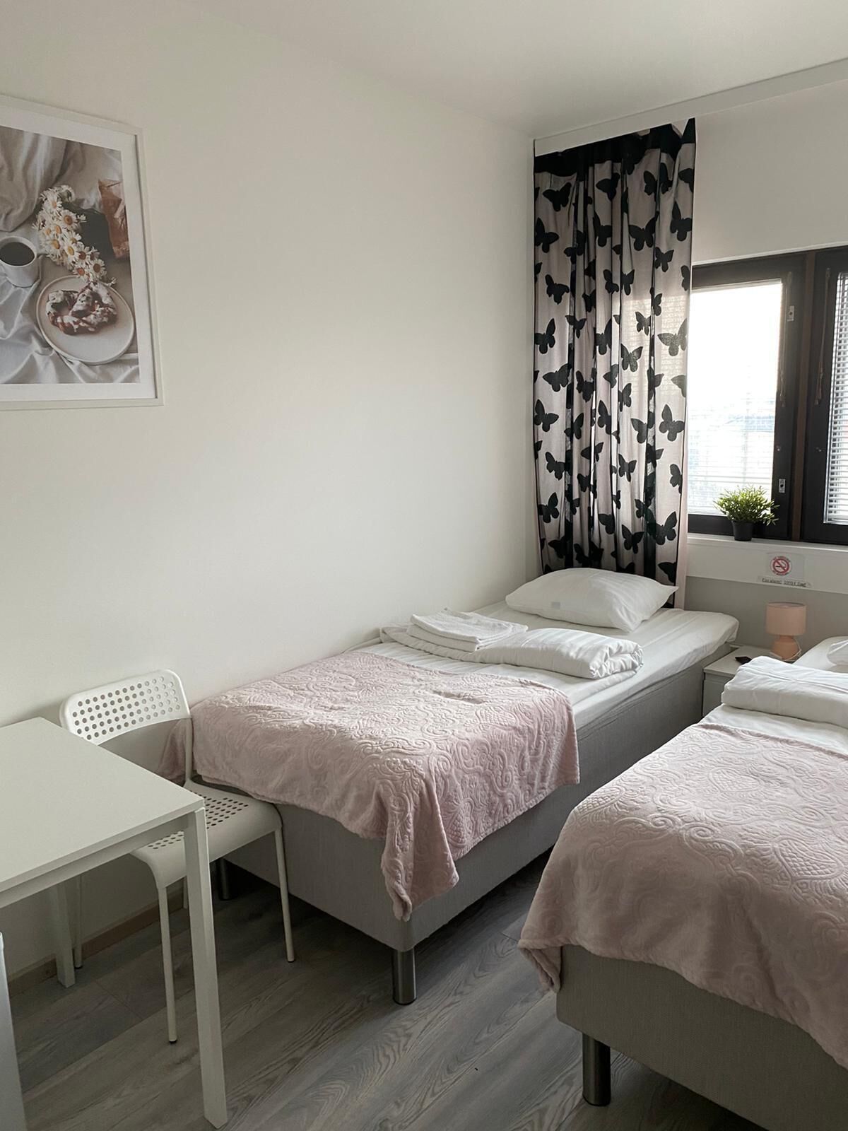 Un dormitorio pequeño y ordenado con dos camas, un escritorio y una silla.