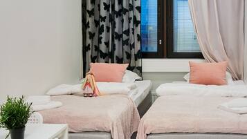 A bedroom with two beds, a desk, and a potted plant.