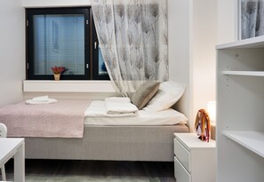 A neatly arranged bedroom with a bed, bedside table, and a window with sheer curtains. - InnTourist Hostel (Helsinki)