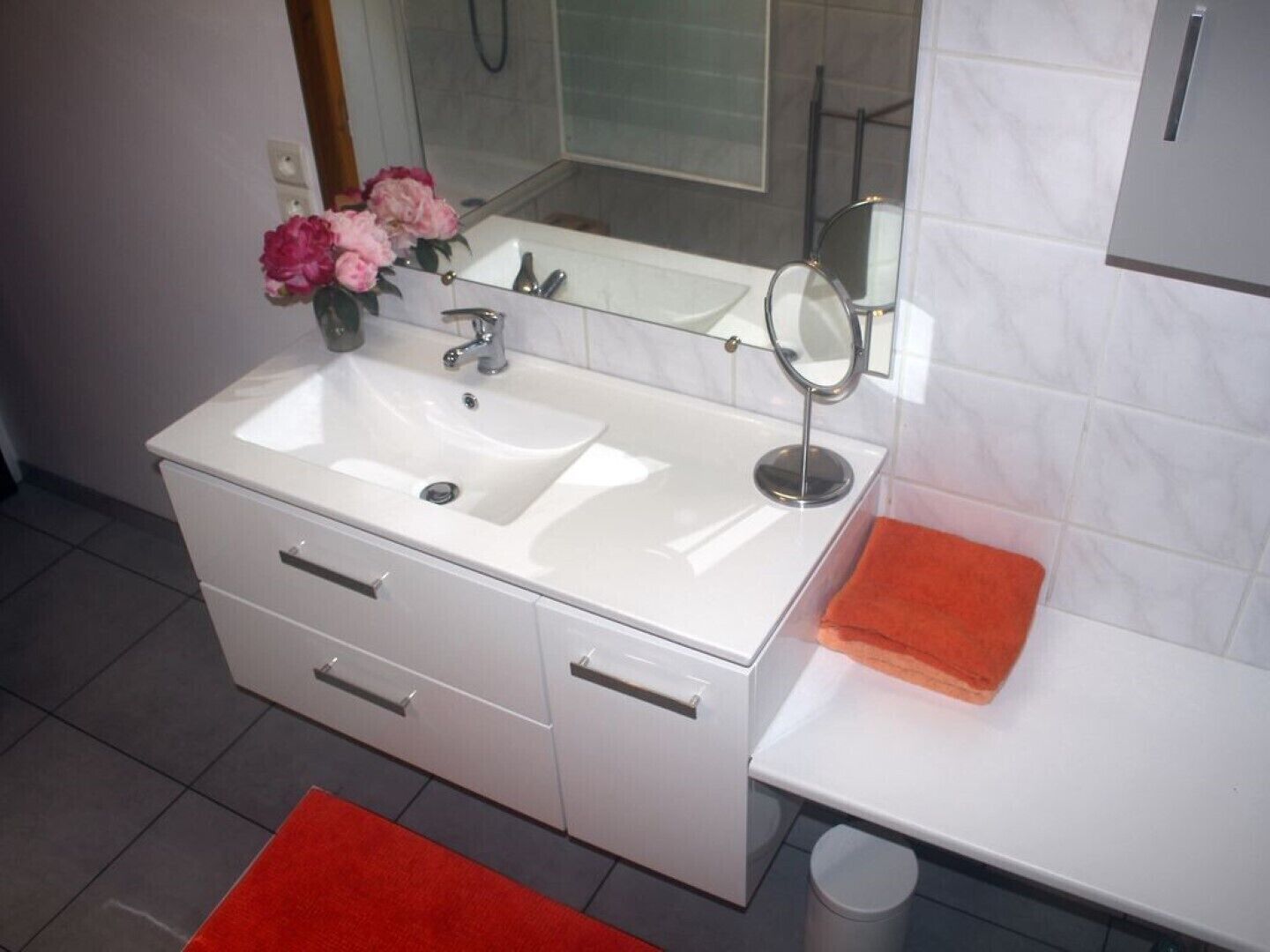 A modern bathroom with a white sink, mirror, and two drawers.