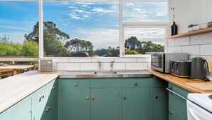 A kitchen with a view of trees and sky through large windows.